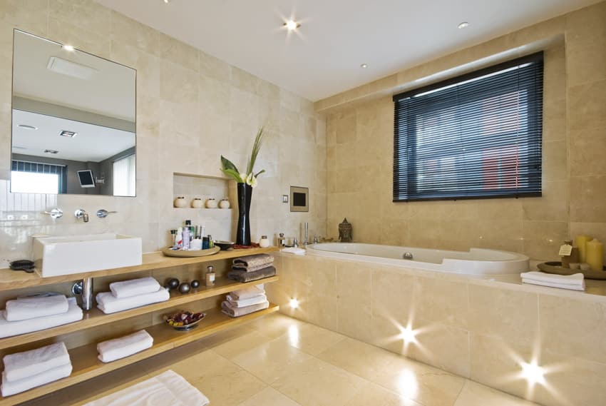 Bathroom with drop in tub tiles mirror shelves window indoor plant