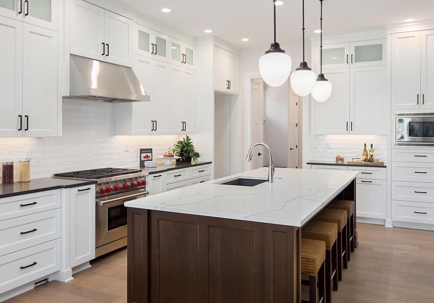 Beautiful kitchen in luxury home with large island pendant lights oven range and hardwood floors
