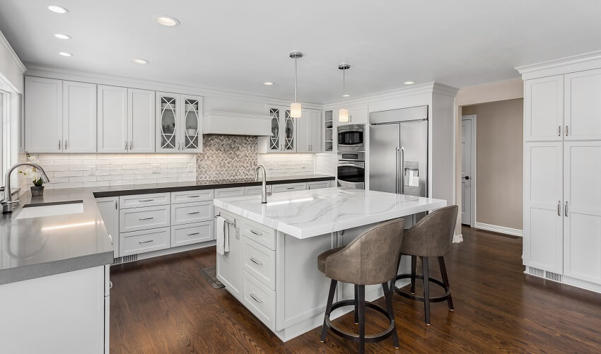 Beautiful kitchen with two sinks and white quartz countertops, and barrel bar stools