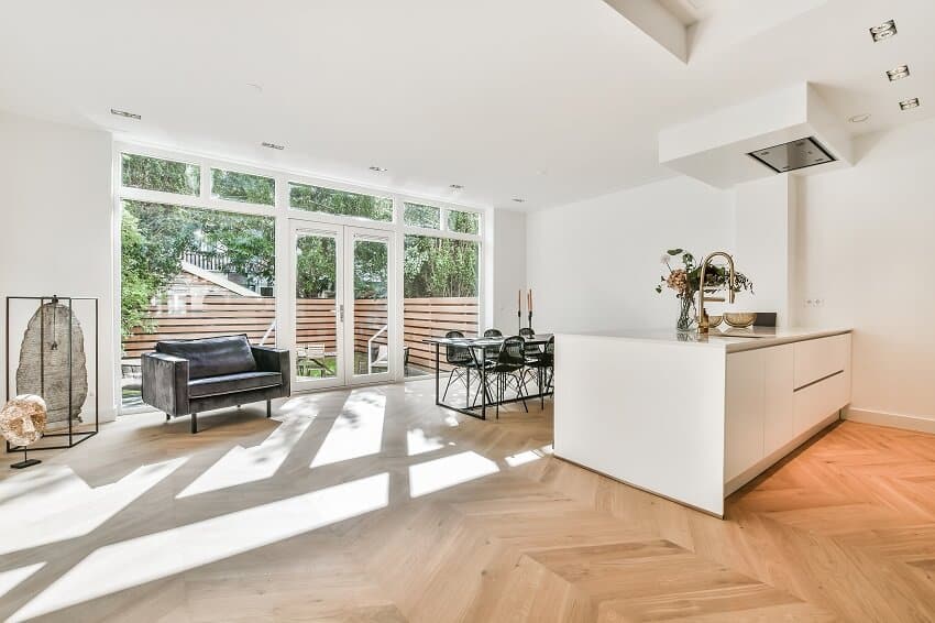 Beautiful open kitchen with wood floor white island dining table sofa and double glass doors