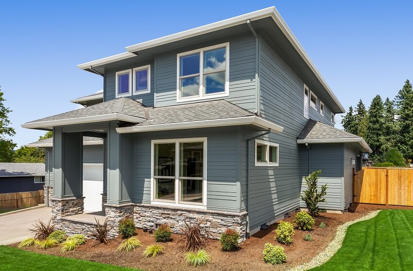 Beautiful suburban grey home exterior with front porch garage plants and green grass