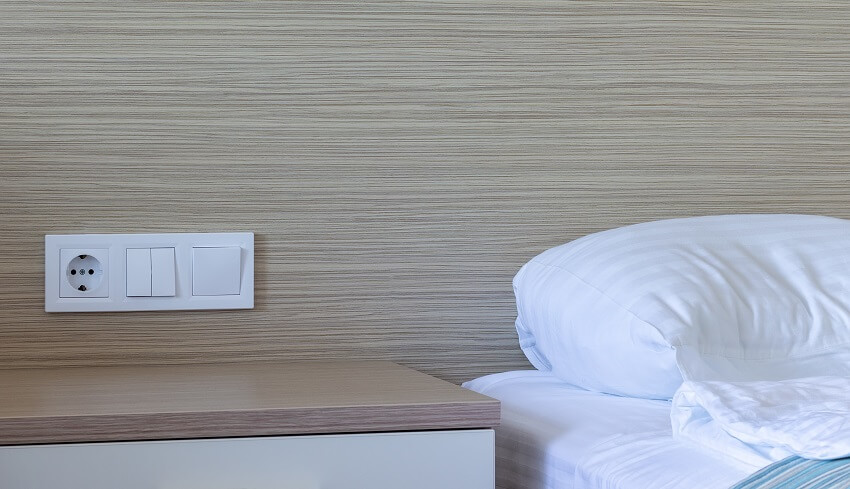 Bedroom with bed bedside table group of socket and switches on wood a wall