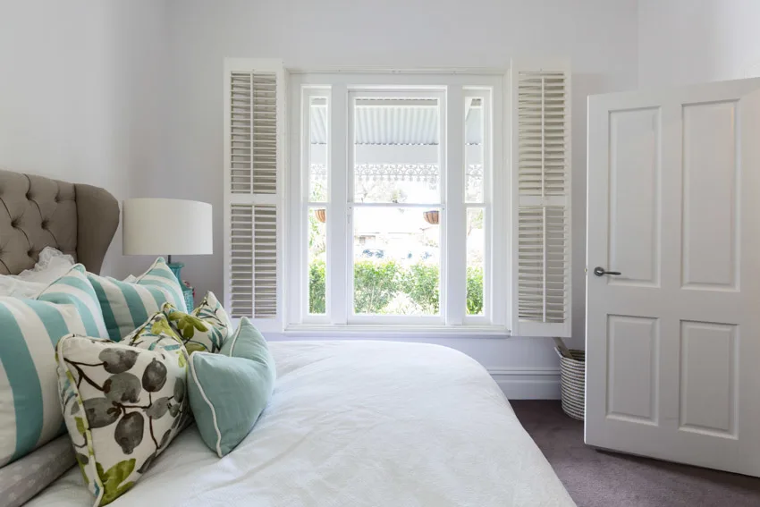 Bedroom with vinyl windows bed interior door pillows shutters