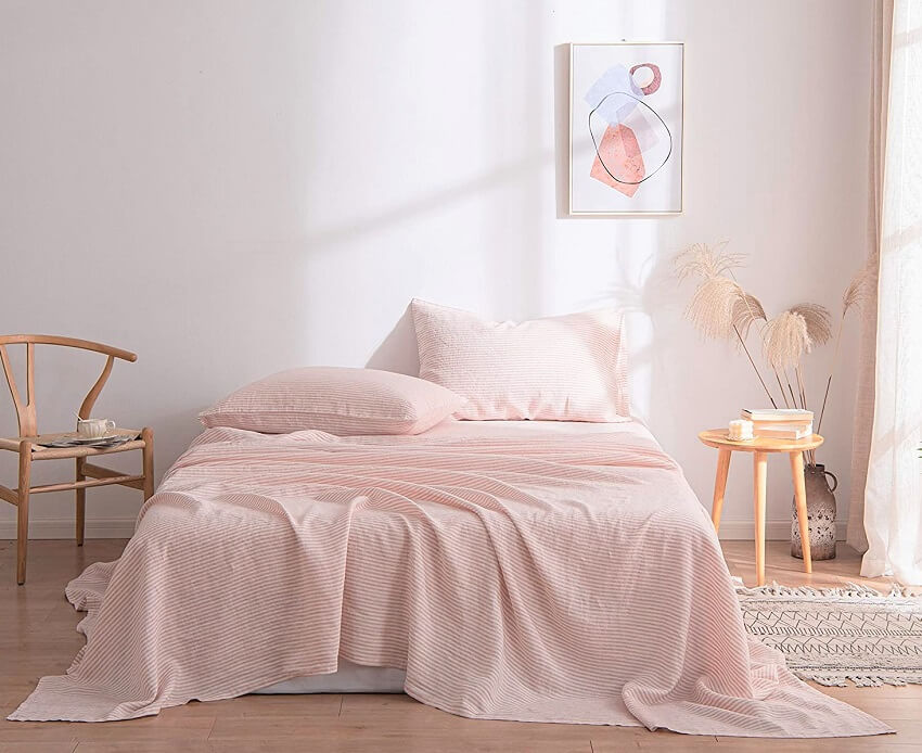 Bedroom with wooden chair and table decors and bed with pink striped roore french linen bed sheet