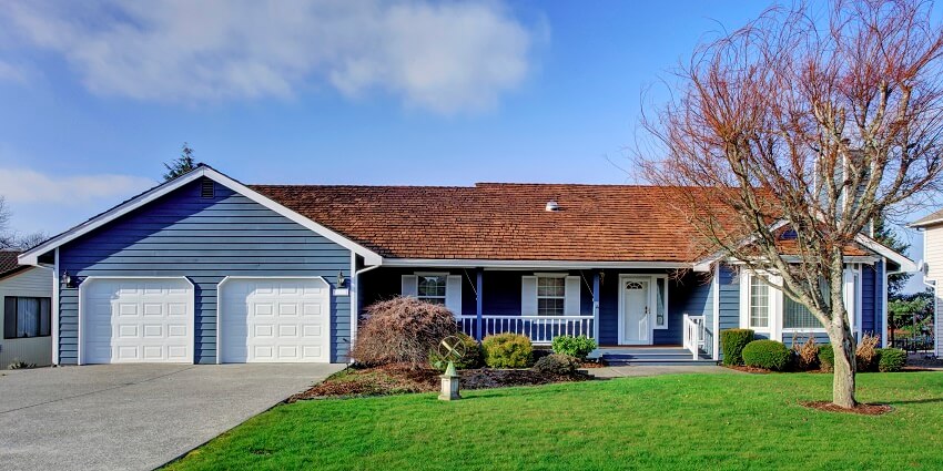 Blue house with a porch large green front yard and garage with driveway