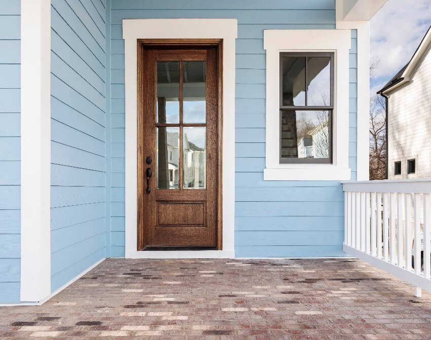 Blue house with a wooden and glass front door and a brick flooring