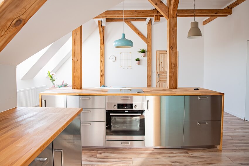 Bright attic kitchen with post and beam pendant lights and stainless steel appliance
