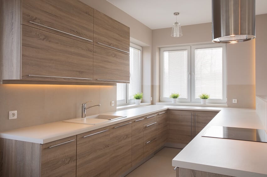 Modern kitchen with veneer cabinets, white solid surface countertops, pendant light and stainless steel circular range hood