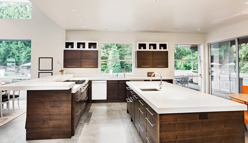 Brown and white painted kitchen with tiered breakfast bar, cement floor and long island with sink