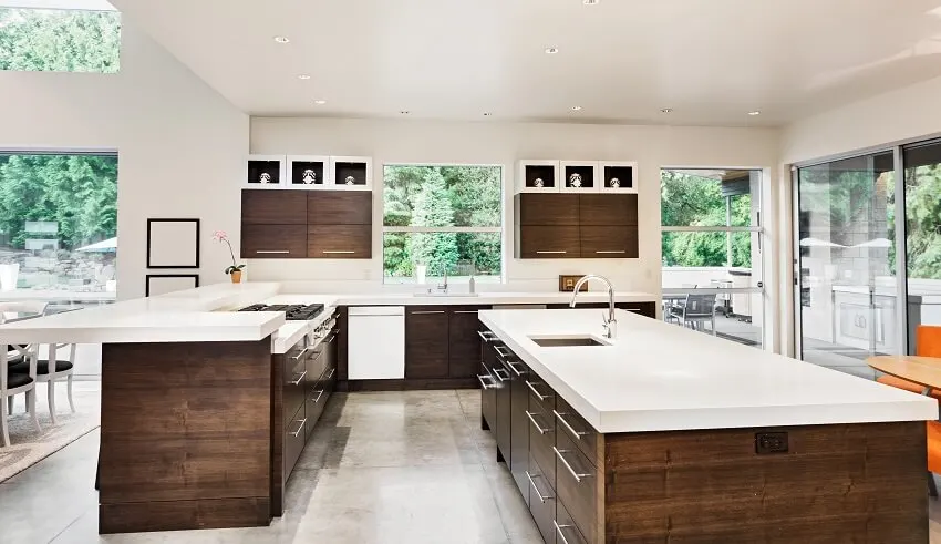 Brown and white painted kitchen with tiered breakfast bar, cement floor and long island with sink