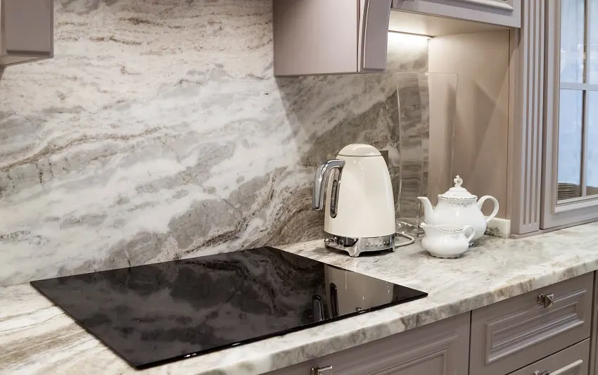 Beautiful Closeup Of Custom Designed Kitchen With Marble Looking Quartz  Countertop And Backsplash Cream Electric Kettle With Porcelain Tea  Accessories On The Marble Countertop Next To Ceramic Hob Stock Photo -  Download