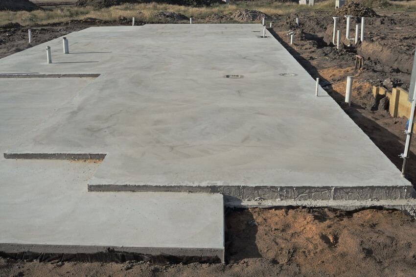 Concrete slab prepared for residential house construction with utility pipes within slab