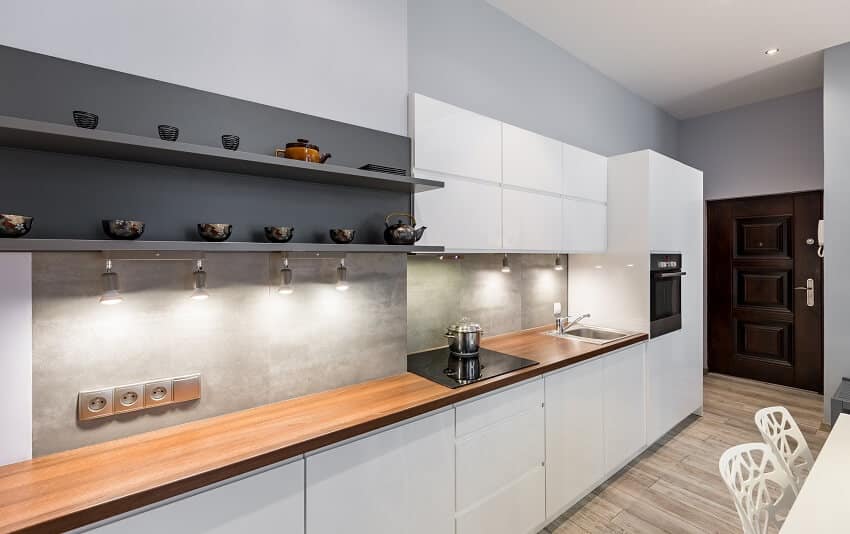 Modern white kitchen with wooden veneer countertop led lighting and gray backsplash
