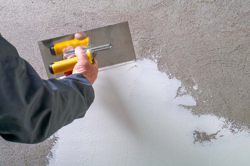 Contractor applying plaster repair wall crack house settling