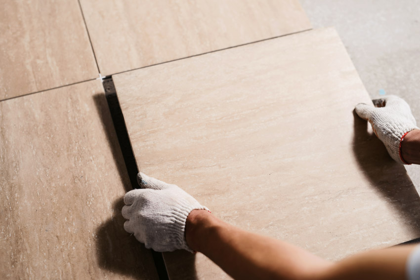 Contractor laying ceramic tiles on top of linoleum floors