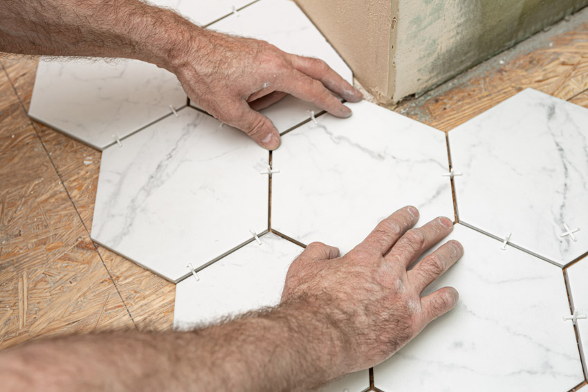 Contractor laying hexagonal tiles on floor