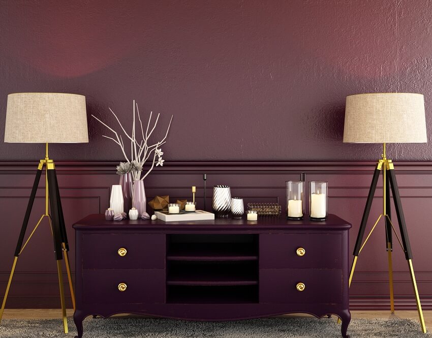 Decor on table cabinet and gold & black lampshades with maroon background and a carpet