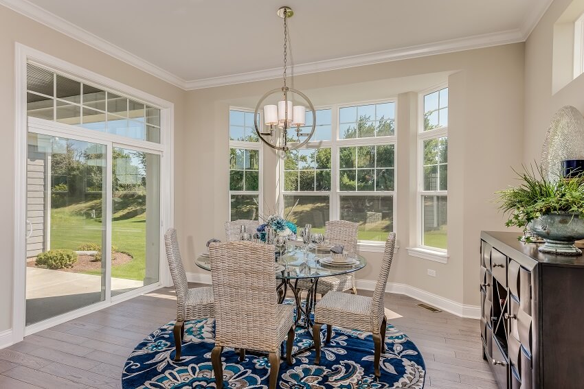 Dining room with blue and white round rug round glass table wood flooring and quick exit out the sliding doors