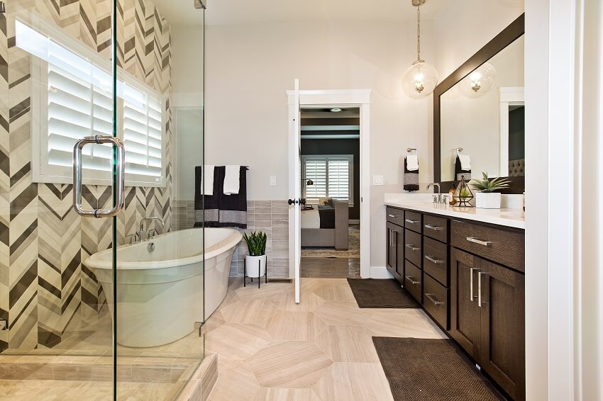 Ensuite bathroom with freestanding bathtub shower brown cabinets decorative plants vanity mirror and tile flooring