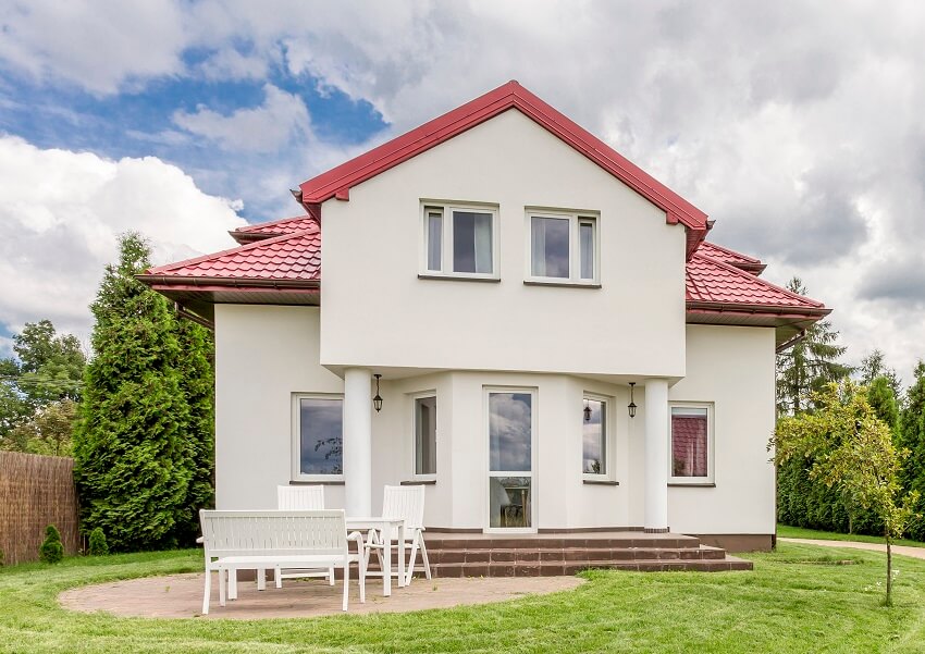 Exterior view of a white villa with a large lawn and bench