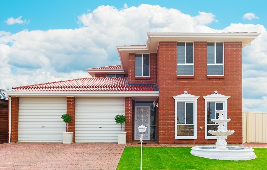 Facade of a modern suburban house with garage and water fountain