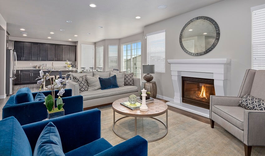 Family room and kitchen with round coffee table round mirror and blue comfortable chairs
