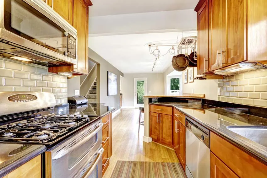 Farmhouse kitchen with honey oak wood cabinets, stove, countertop, and tile backsplash