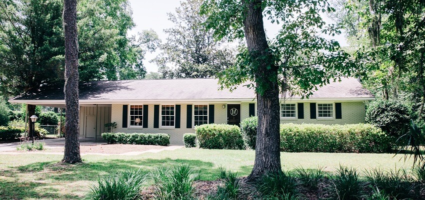 Front view of exterior white cream brick house with yard and walkway