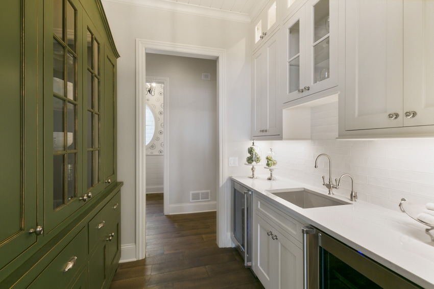 Galley style kitchen green and white cabinets wood floor countertops sink