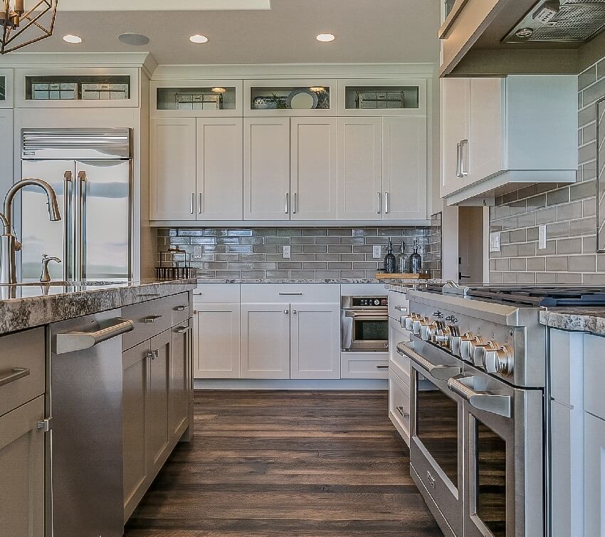 Gorgeous kitchen interior featuring wooden floors granite countertops cabinets and subway backsplash