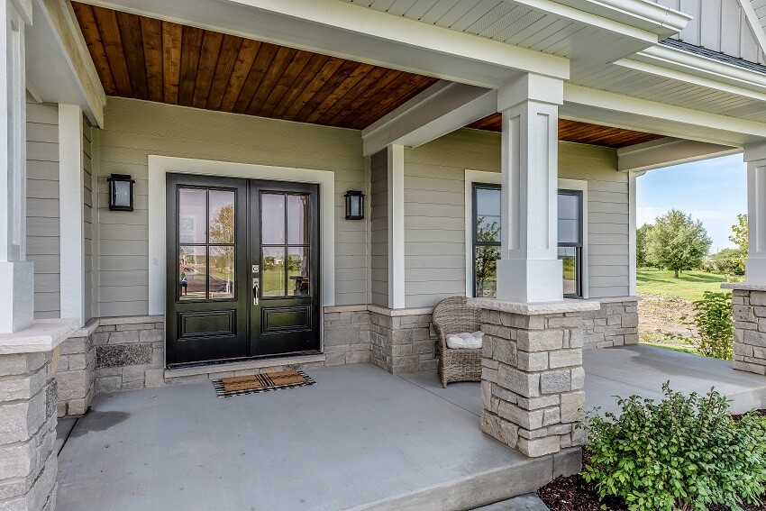 Home entrance with columns wood and stone siding porch and double door