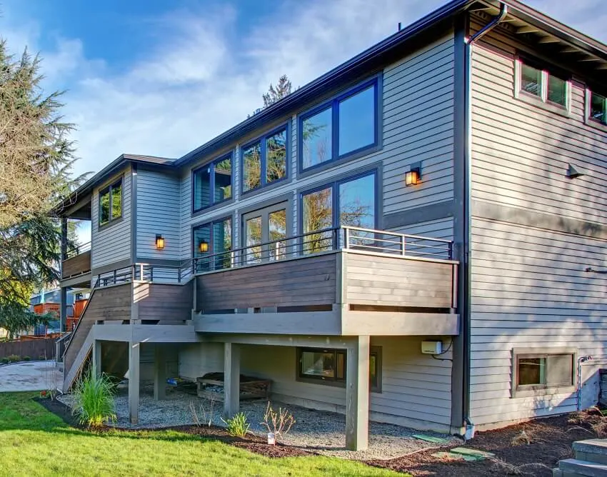 Exterior with oversized deck overlooking a garden and a basement with windows