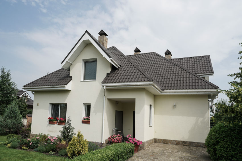 House exterior with metal roofing white wall paved driveway windows