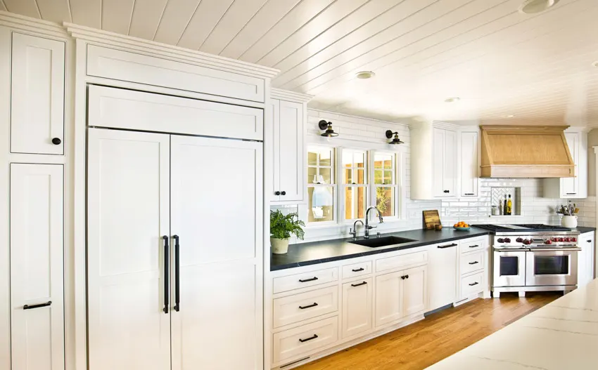 Kitchen galley farmhouse style wood floor ceiling black countertop white cabinets hood windows