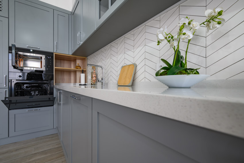 Kitchen space with herringbone backsplash countertop gray cabinet