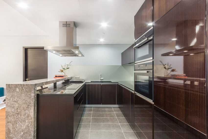 Kitchen with dark wood cabinets tiled flooring backsplash hood center island lighting