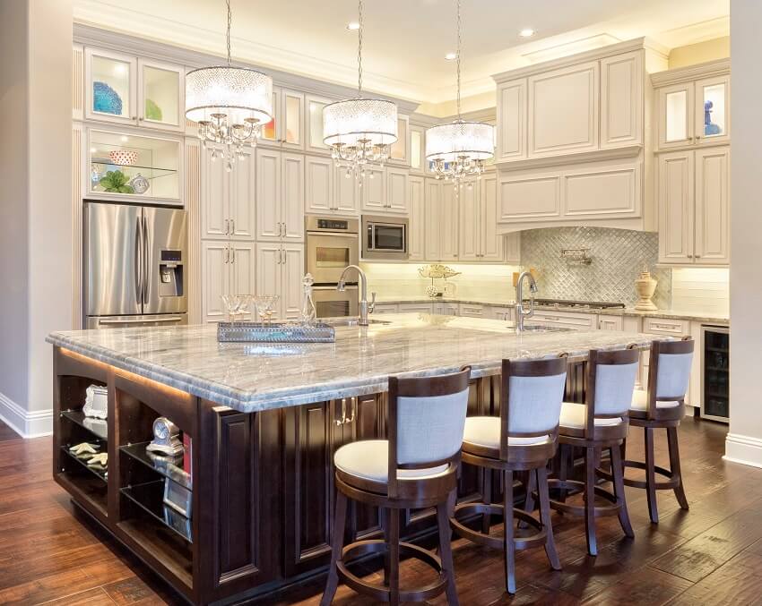 Kitchen with hardwood floors white cabinets bar stools pendant lights and large island with two sinks