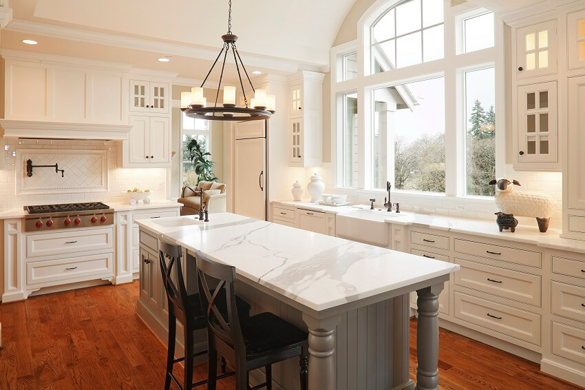 Kitchen with natural light decors white cabinets hardwood floors bar stools and grey island with marble countertop
