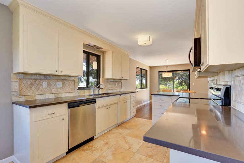 Kitchen with white cabinets travertine floors countertop windows oven