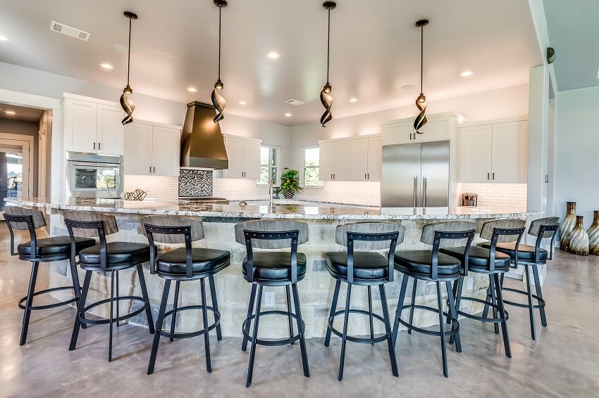 Large new kitchen with four pendant lights and stools around boomerang shaped kitchen island