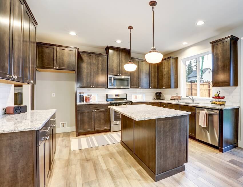 Light filled kitchen with kitchen island floor panels natural brown cabinets topped with granite countertops and paired with white backsplash