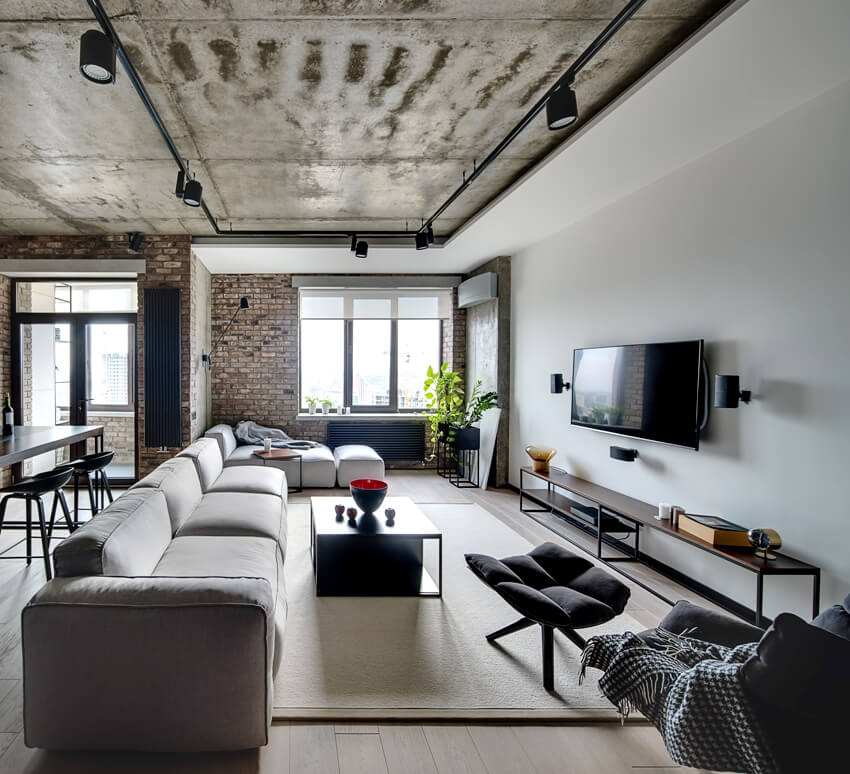 Living area with furniture white and brick walls and a concrete cove ceiling