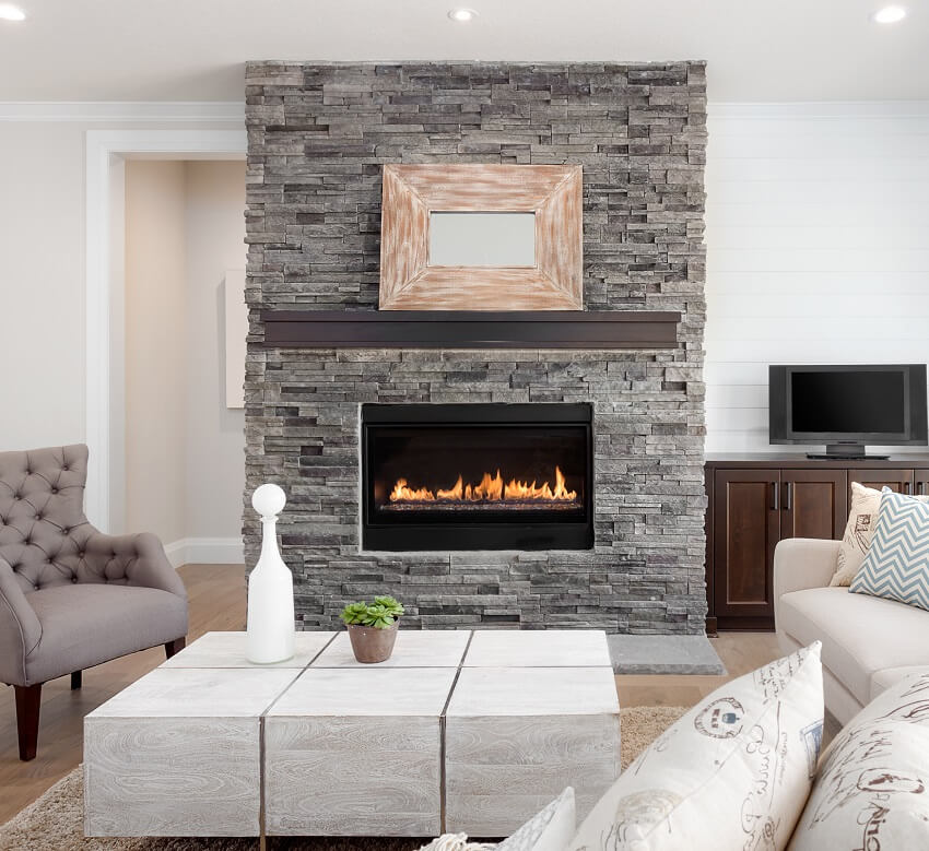 Interior with hardwood floors couch and fireplace with surround that stretches to ceiling