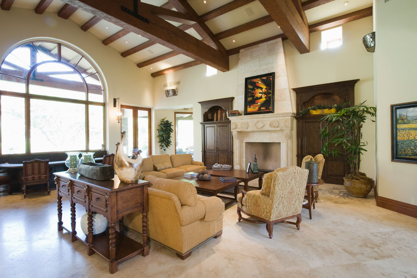 Living room with coffered ceiling, wood beams, couch, sofa table, chairs, windows, and indoor plants