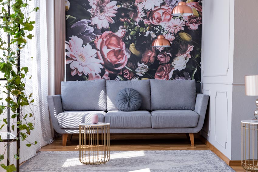 Living room with fabric floral wall covering gray couch rug windows