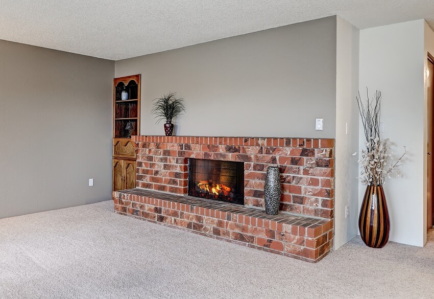 Room with grey walls carpet floor and red fireplace bricks