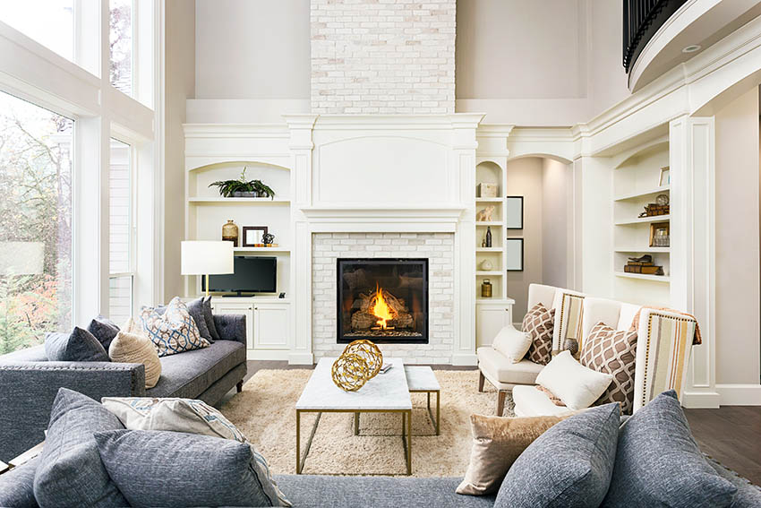 Living room with painted white fireplace white built in shelving and high ceilings