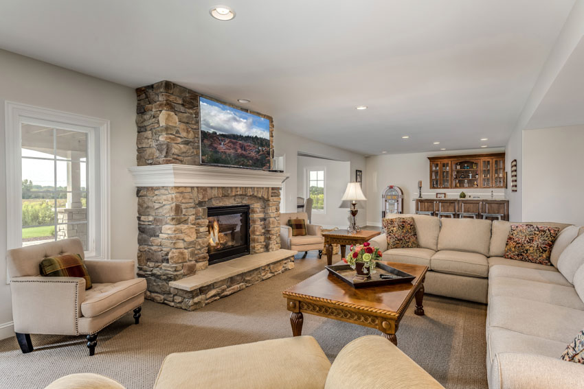 Living room with stone fireplace painting ceiling couch chairs lamps coffeetable windows