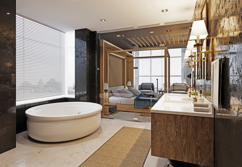 Luxurious bathroom with black marble walls large bathtub shower double washbasin and view of the bedroom through glass door
