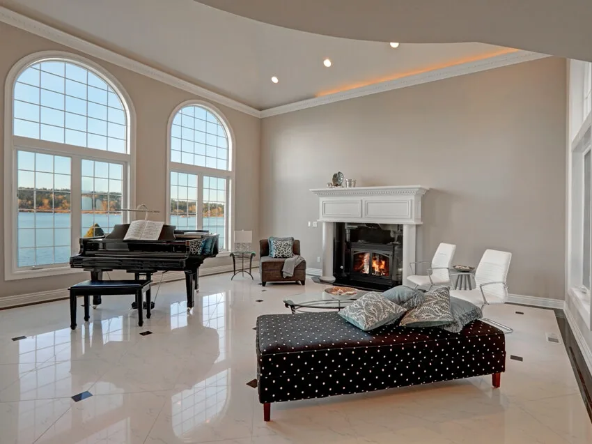 Luxury high ceiling living room features large arched windows traditional fireplace black grand piano and cozy sitting area